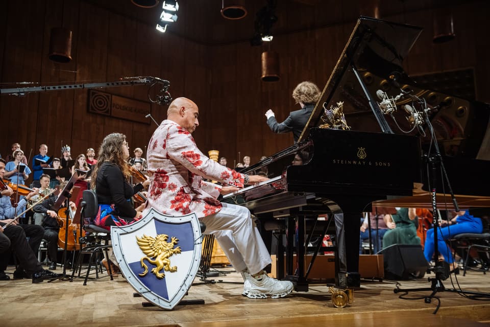 Pianista w marynarce w czerwone kwiaty gra na Steinwayu w studiu Polskiego Radia; przy scenie tarcza ze złotym gryfem, dalej dyrygent.